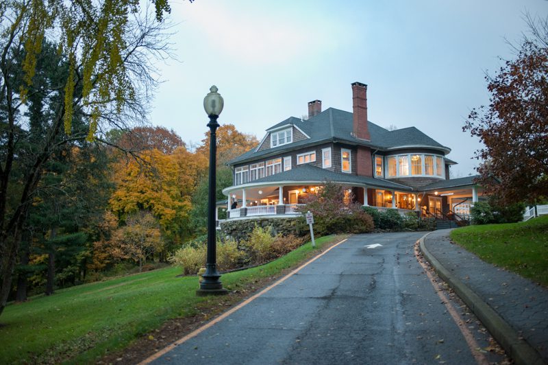 the mansion lit up surrounded by fall foliage at dusk